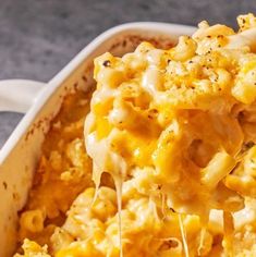 a casserole dish with macaroni and cheese being lifted by a fork