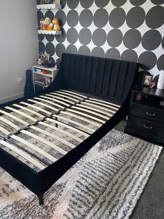 a black and white bedroom with polka dot wallpaper on the walls, bed frame