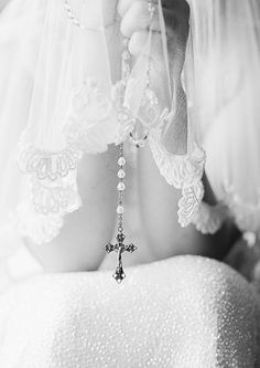 black and white photograph of a woman wearing a veil with a cross hanging from it