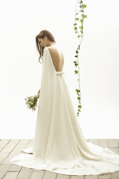 a woman in a white wedding dress standing on a tile floor with her back to the camera