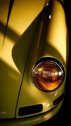 the front end of a yellow sports car with its hood up and headlight on