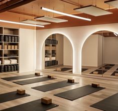 an empty yoga room with rows of mats on the floor and shelves full of books