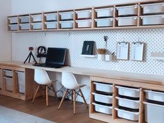 a desk with two laptops and several bins on the wall next to it