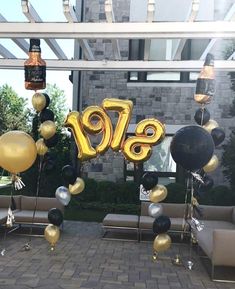 an outdoor event with balloons, couches and chairs in front of the entrance to a building