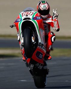 a man riding a motorcycle on top of a race track with his hand in the air