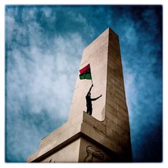 a person holding a flag on top of a tall building