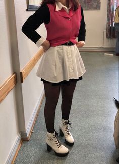 a woman standing next to a wall with her hands on her hips wearing white and black shoes