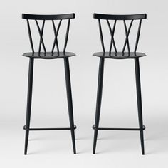 two black barstools sitting next to each other on a white surface with one chair in the middle