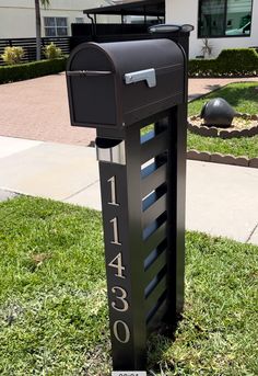 a black mailbox sitting in the grass next to a building