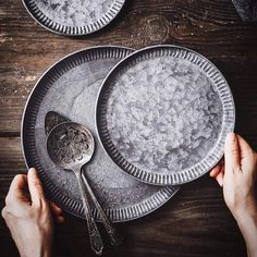 two people are holding spoons and plates with food on them, one is empty