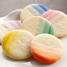 four different colored cookies on a white plate