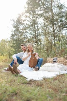 a man and woman sitting on a blanket in the grass with an old photo frame