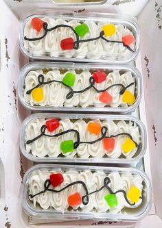 four plastic containers filled with white frosting and colorful candy