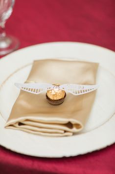 a place setting with napkins, cupcake and wine glass on the tablecloth