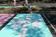 a man kneeling down on the ground in front of a parking lot painted with different colors