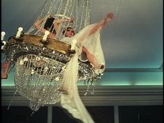 a chandelier hanging from the ceiling with two people standing on top of it