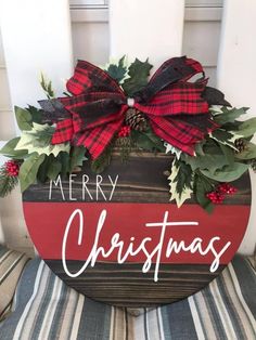 a merry christmas sign on a chair with holly and red ribbon hanging from the back