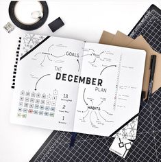 an open planner sitting on top of a cutting board next to scissors and tape with the words december written in it