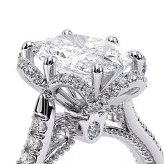 an engagement ring with a cushion cut diamond surrounded by round brilliant diamonds and pave set shoulders