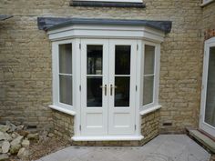 a white double door with two windows in front of a brick wall and stone walkway