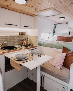 a kitchen area with a table, sink and stove top oven next to a bed