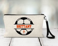 "Personalized Soccer Zippered Pouch. Personalized with team colors and name.  Be sure to include all personalization info when checking out.  Please list 2 team colors and player name(s) & number(s) in the personalization box when checking out.  We will send a proof for any team orders over 12 or anytime we may have a question about personalization info.  Please check Etsy messages for your proof.   These linen zippered pouches are the perfect gift for sports teams!  Can be used for accessories, makeup, phones, tech accessories and more.  Perfectly sized to fit in sports bag, travel bag, or backpack.  Measures 9.25\" x 6.5\".  Black wrist strap attached with a lobster clasp.   If you don't see a sport or design you need please message us and we can help!  20% discount for team orders of 12 Customizable White Bags For Sports Events, Sporty Personalized Sports Bag, Personalized Sporty School Bag, Sporty Personalized School Bag, White Letter Print Sports Bag, Personalized Sporty Bags For Sports Events, Customizable Sporty School Bags, Sporty Personalized Bag For Sports Events, Customizable School Spirit Bag For Everyday