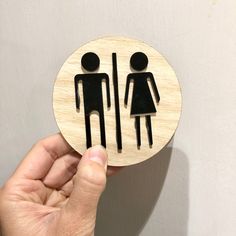 a person is holding up a wooden sign with a man and woman symbol on it