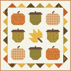 an orange and green quilt with pumpkins, apples, and leaves on the front