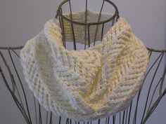 a white knitted scarf sitting on top of a metal stand