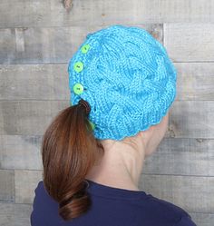 a woman wearing a blue knitted hat with green buttons on the back of her head