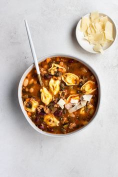 a bowl of soup with tortilla shells, meat and cheese on the side