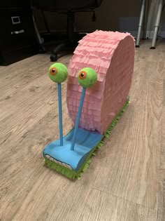 a pink and green sculpture on top of a wooden floor next to a computer desk