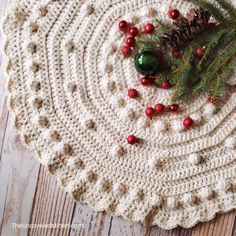 a crocheted placemat with pine cones and berries on it, next to a green christmas ornament