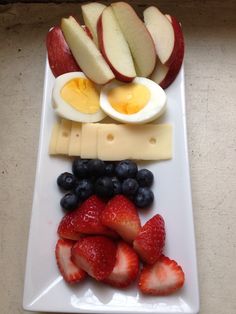 a white plate topped with fruit and an egg on top of cheese next to sliced apples