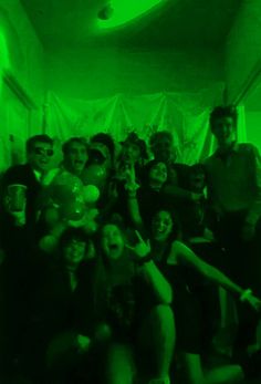 a group of people posing for a photo in a room with green light on the ceiling