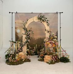 an archway decorated with flowers and greenery in front of a painting