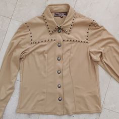 Vintage Women's Button Down Shirt From Double D Ranch Yoakum Texas. Size Is Xs, Please See Measurements Below Like Brand New. The Color Is Tan, Resembles Camel Has Unique Buttons Along The Front And Studded Details All Around The Yoke, Collar, Back Of Shirt, And End Of Sleeves. 100% Polyester Fabric, Very Soft Fabric Underarm To Underarm 17.5 Shoulder To Bottom 19.5 Western Style Tops With Buttons For Workwear, Western Style Tops With Button Closure For Work, Designer Fitted Tops With Button Cuffs, Fitted Beige Tops With Button Cuffs, Fitted Western Tops With Button Closure, Retro Button-up Top For Ranch, Snap Button Button-up Tops For Rodeo, Western Button-up Tops With Pockets, Button-up Tops With Snap Buttons For Rodeo