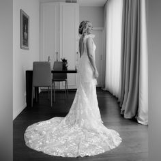 a woman in a wedding dress looking out the window