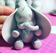 a small elephant figurine sitting on top of a pink table next to a person's hand