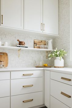 a kitchen with white cabinets and gold pulls on the handles, drawers, and shelves