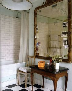 a bathroom with black and white checkered flooring, a large mirror on the wall