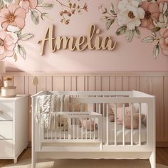 a baby's room decorated in pink and white with flowers on the wall above it