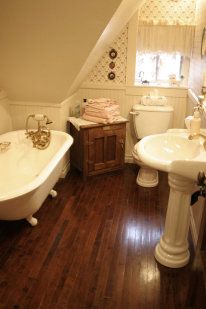 an attic bathroom with wood floors and white fixtures, including a claw foot bathtub