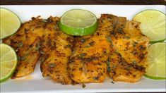 grilled chicken with limes and lemon wedges on a white plate