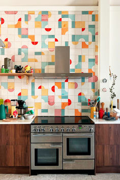 An installation of Smink Studio tiles in a colourful, happy pattern of red, orange, blue and yellow. Tile Feature Wall, Backsplash Installation, Printed Tiles, Converted Church, Patterned Kitchen Tiles, Dark Wood Cabinets