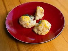 three biscuits on a red plate sitting on a wooden table