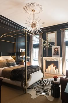 a bedroom decorated in black and white with a canopy bed, zebra print rugs, candles and pictures on the wall