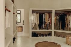 a walk in closet filled with lots of clothes and shoes next to a rug on the floor