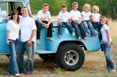 a group of people sitting on the back of a blue truck with kids in it