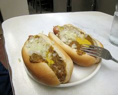 two hot dogs with chili and cheese on a plate